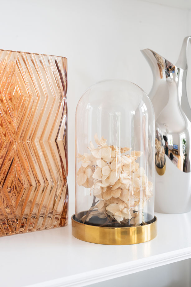 Et skønt stilleben i den indbyggede reol bestående af en vase fra Hübsch, tørret Hortensia og en kande fra Georg Jensen.