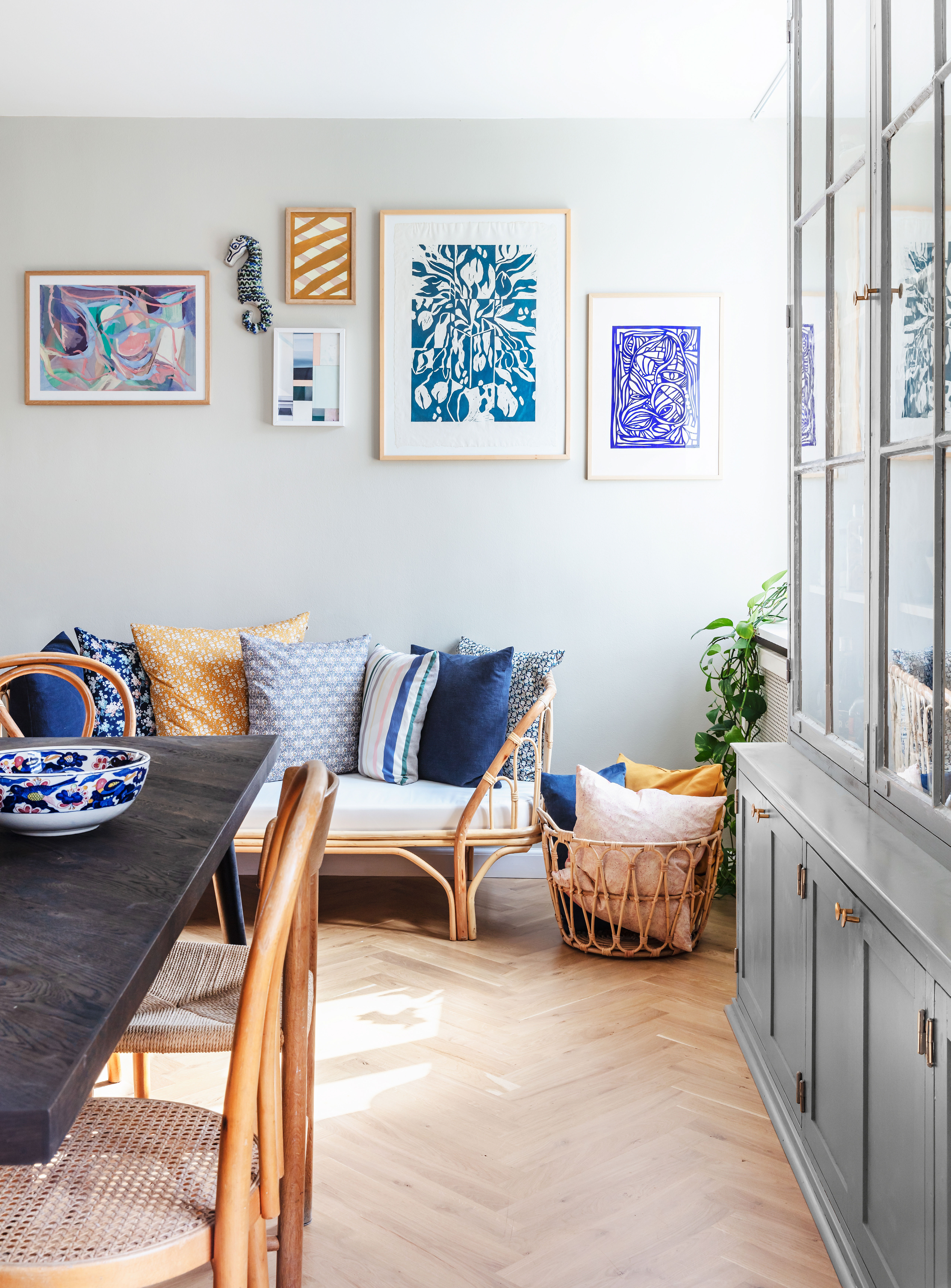 For enden af spisebordet står en hyggelig daybed fra Petite Legarth, hvor også libertypuderne er fra. Billederne er fra venstre fra @curated_copenhagen, søhest i keramik fra @_setaku_, unikaværk i karry og rosa af Mathias Malling Mortensen, unikaværk i pasteller fundet på auktion hos Bruun Rasmussen, tryk af Kristine Hellesøe Appel fra Finders Keepers og papirklip i ramme fra Hein Studio.
