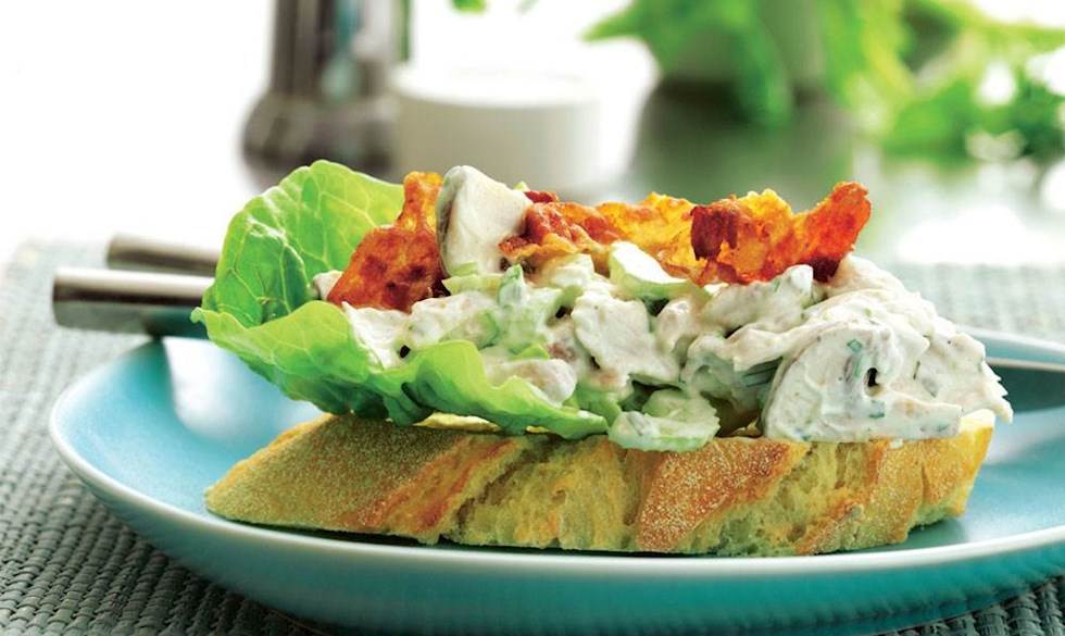 Den færdige hønsesalat — eller rettere kyllingesalat — anrettes på brød med salatblade og pyntes evt. med sprødstegt bacon... Nem og lækker hønsesalat