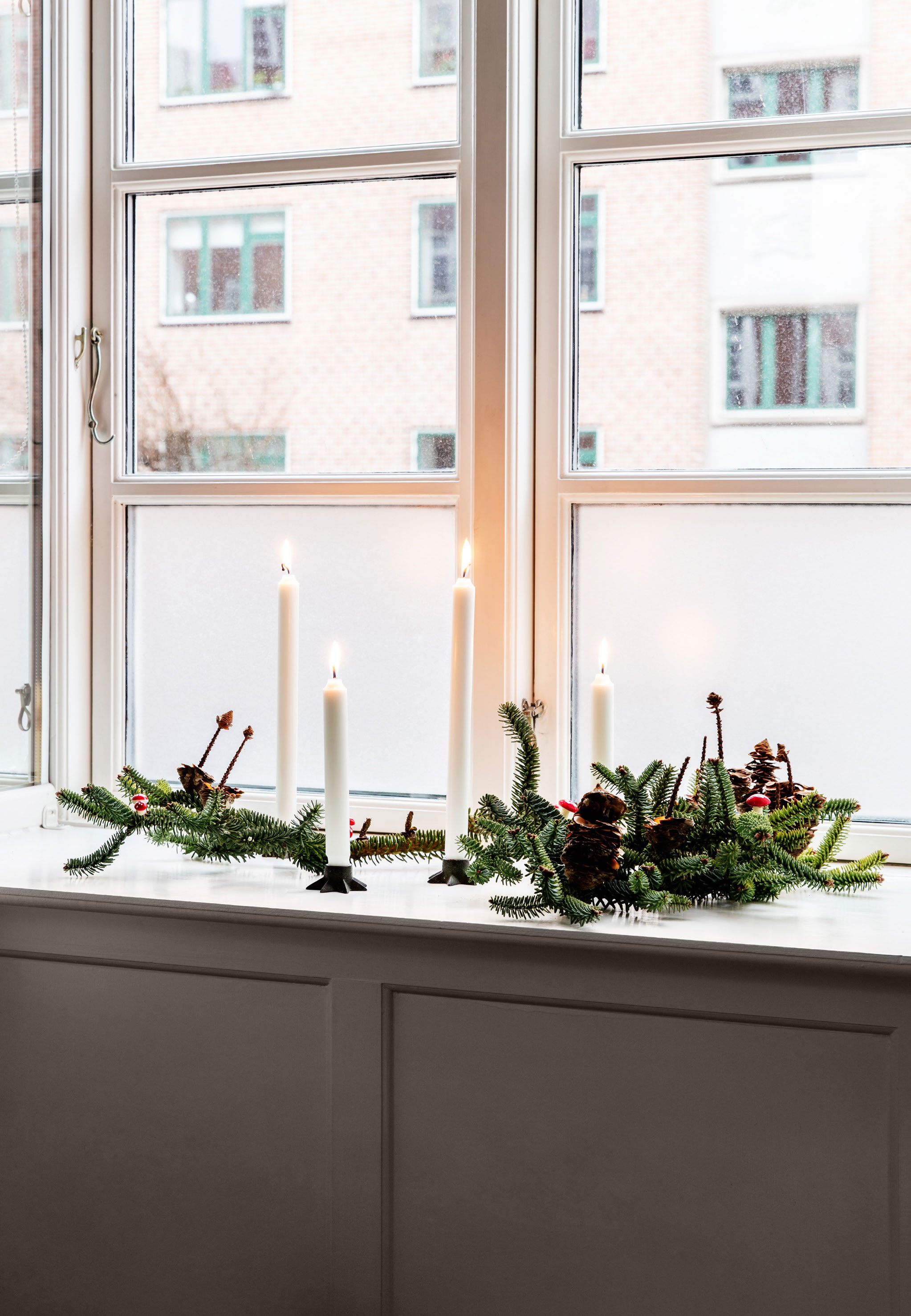 Stuevinduet er pyntet med ædelgran med kogler samt lys sat i gamle stjernestager.