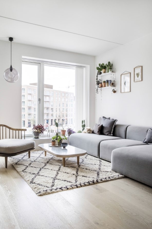 Naturmaterialer og afdæmpede nuancer af blå og grå går i dialog med lejlighedens spritnye rum. Her i stuen, der er indrettet med sofa fra Hay, sofabord og lænestol fra &Tradition og gulvtæppe fra Ellos.