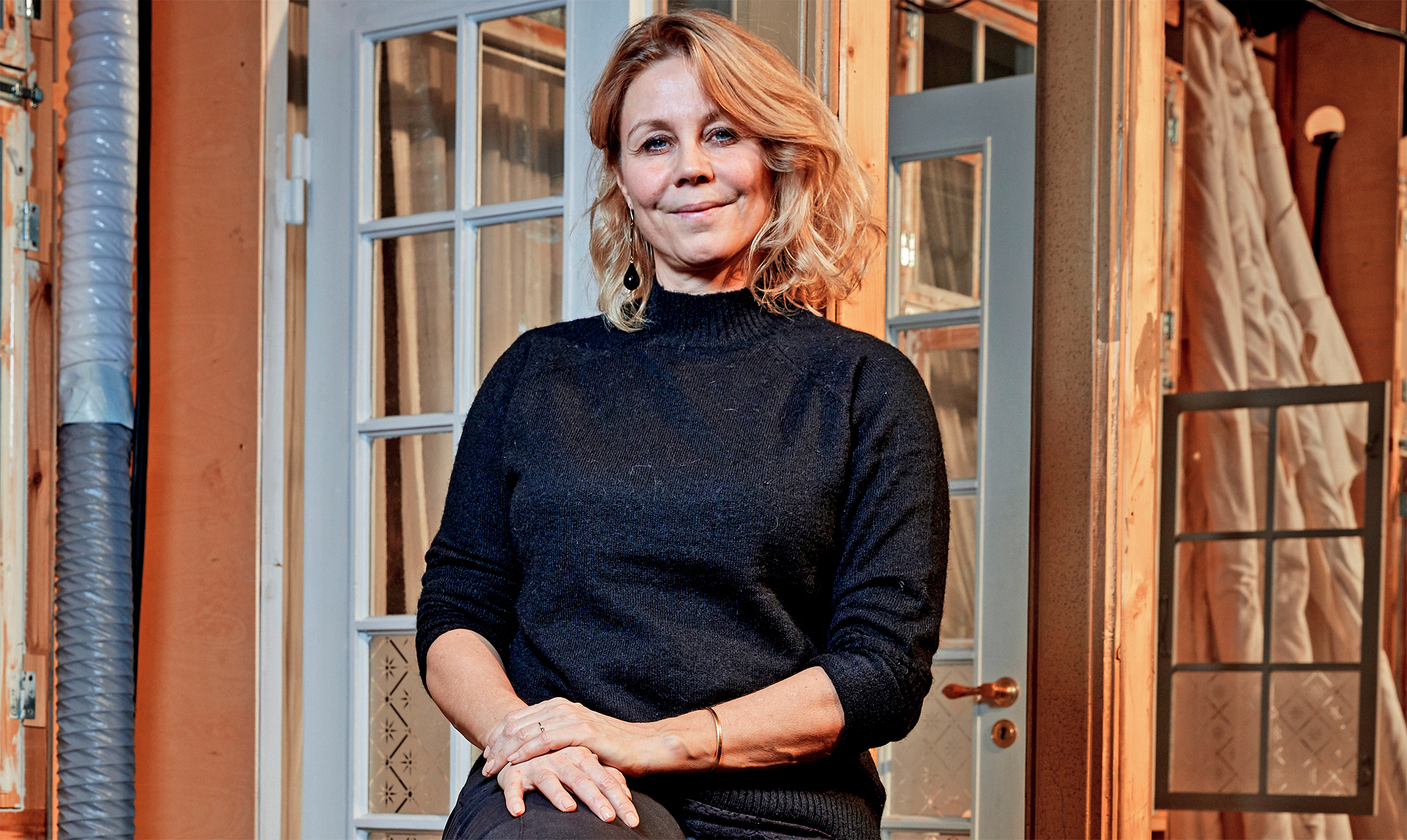 De hvide døre bag den smukke skuespillerinde fører lige ind i "Badehotellets" reception. Det meste af serien optages nemlig her i "Badehotellets" studie i Albertslund. Anne Louise Hassing