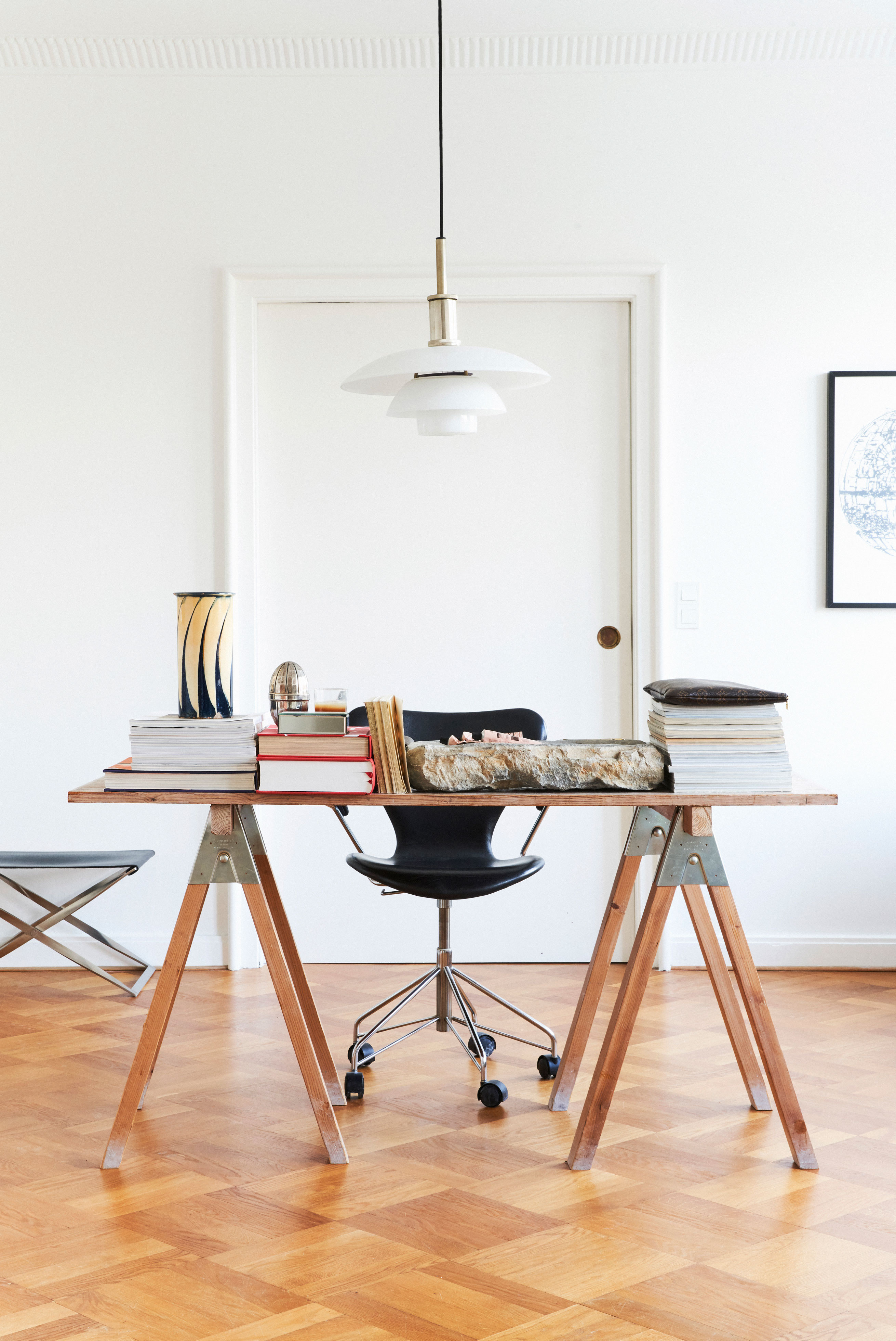 Symmetri og rene linjer definerer hjemmekontoret. Skrivebordet er lavet af Charlottes farfar til Charlottes mor. Stolen er Arne Jacobsens 3207 i sort læder med hjul, mens lampen er en PH i glas fra Charlottes mormor og morfar, vasen er fra Kähler og vintage.