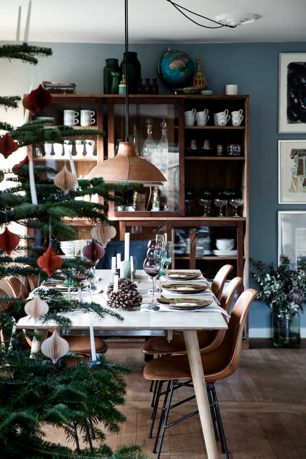 Julebord med farvede glas, gran og kogler.