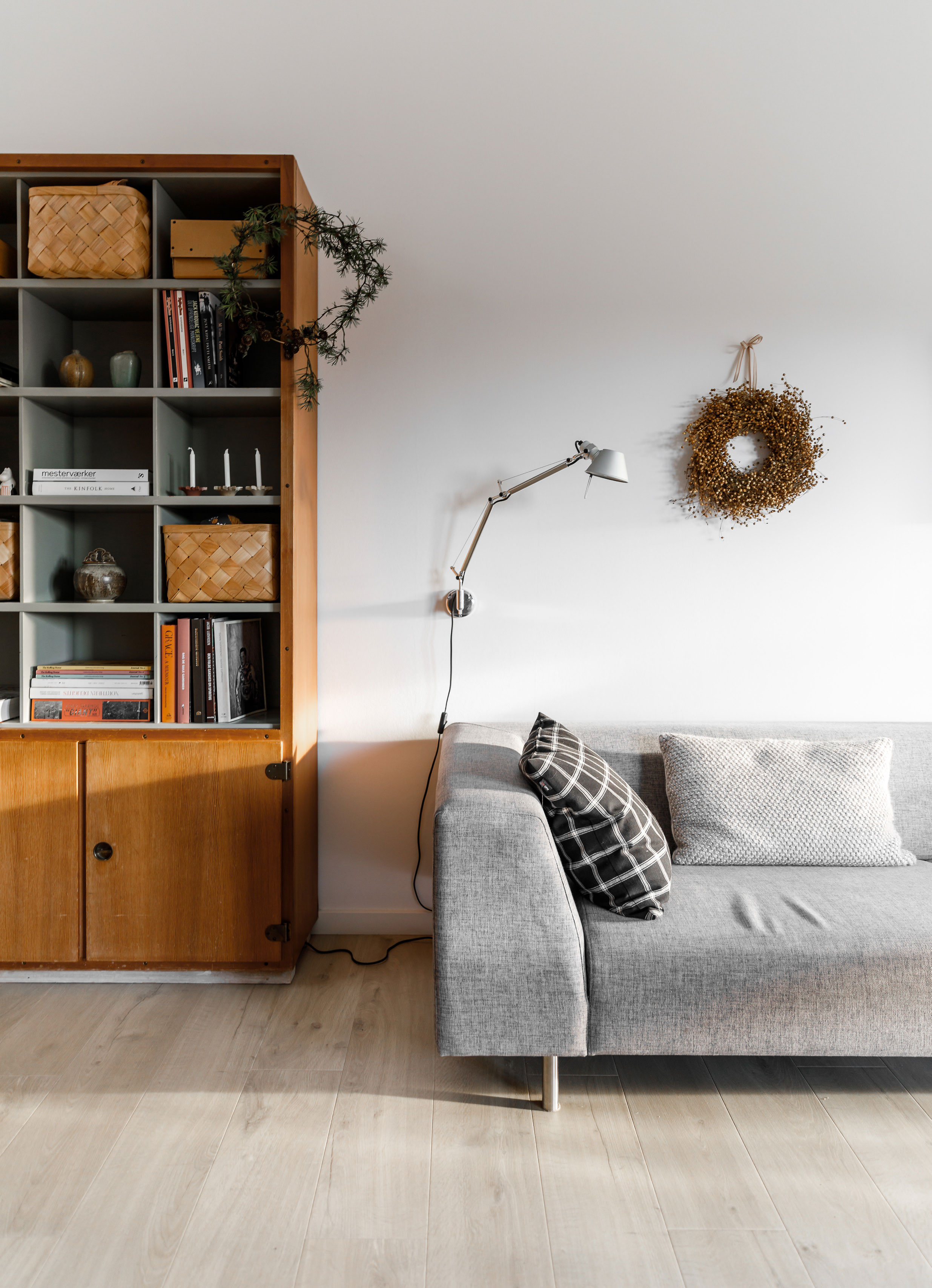 Ida er begyndt at binde små, enkle kranse, som den der hænger på reolen. Hørkransen over sofaen er fra Loui’s blomster i Aalborg. Sofaen er fra Bolia og lampen er fra Artemide