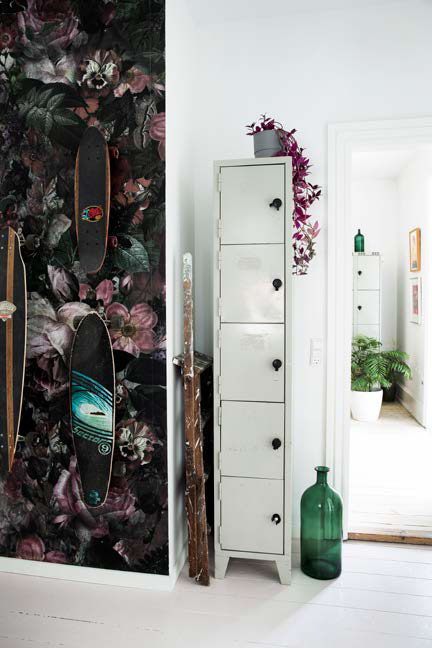 En væg i entreen er dekoreret med et flot blomstret tapet fra Mr Perswall. På redskabsgrebene hænger familiens skateboards, som stadig bruges flittigt. Skabet er fra Marias tidligere job.