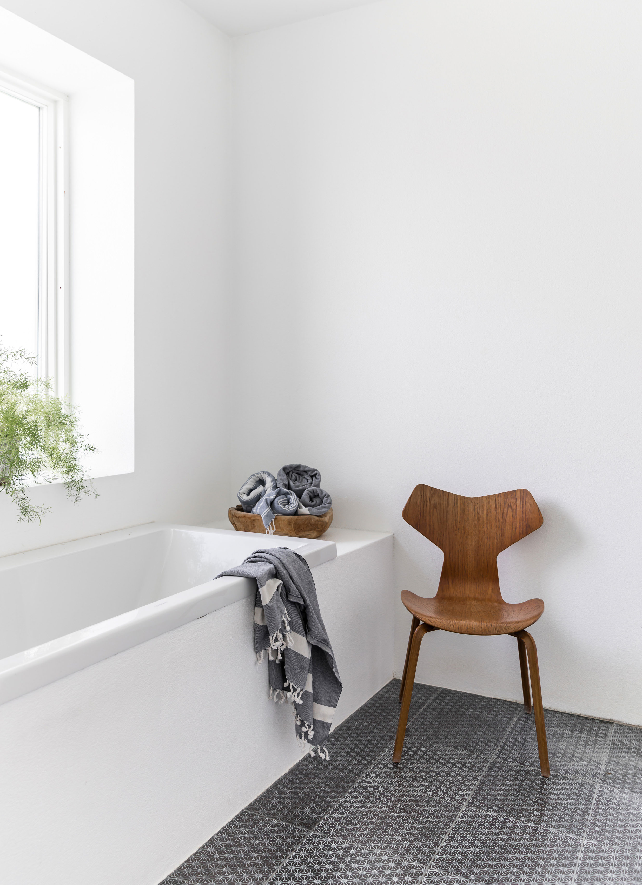 Da badeværelset blev renoveret, kom der grå fliser fra Made a Mano på hele gulvet som modspil til de hvide vægge. Fadet med håndklæder er fra Muubs, Grand Prix-stolen, designet af Arne Jacobsen, er købt på auktion.