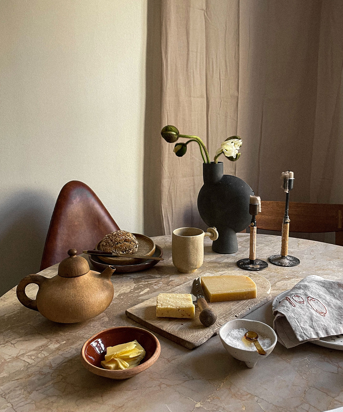 Bordet er dækket med vase fra 101 Copenhagen, lysestager fra MENU, krus fra Aarhus Studio, japansk saltskål, serviet fra Stilleben, tallerken fra Julie Damhus, vintage tekande og skærebræt.