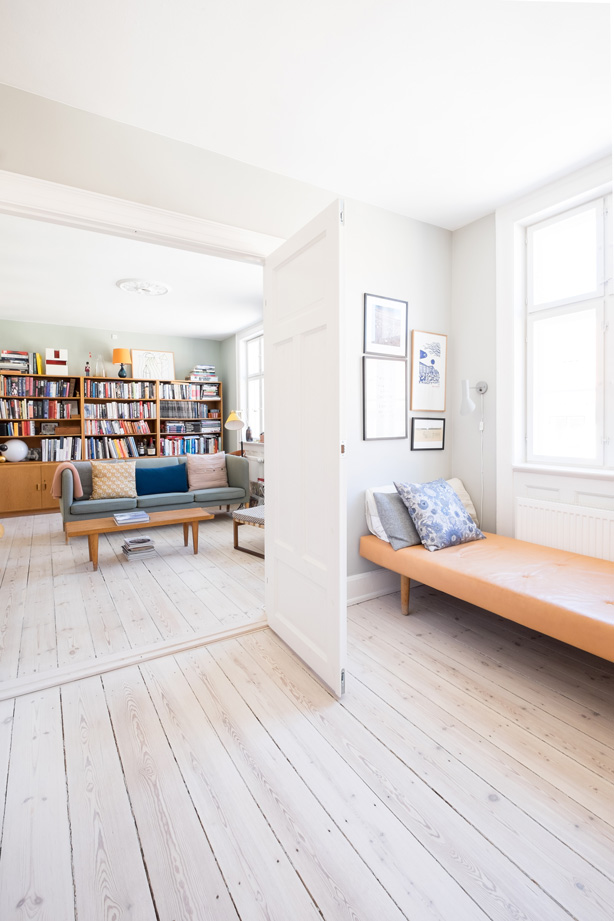 Det smukke lysindfald ses i alle rum, også her mellem spisestuen og stuen. Daybed'en er designet af Wegner og læselampen over er AJ designet af Arne Jakobsen. Sofaen i dagligstuen er en vintage Wegner, og sofabordet er et Børge Mogensen, som parret også har fundet brugt.