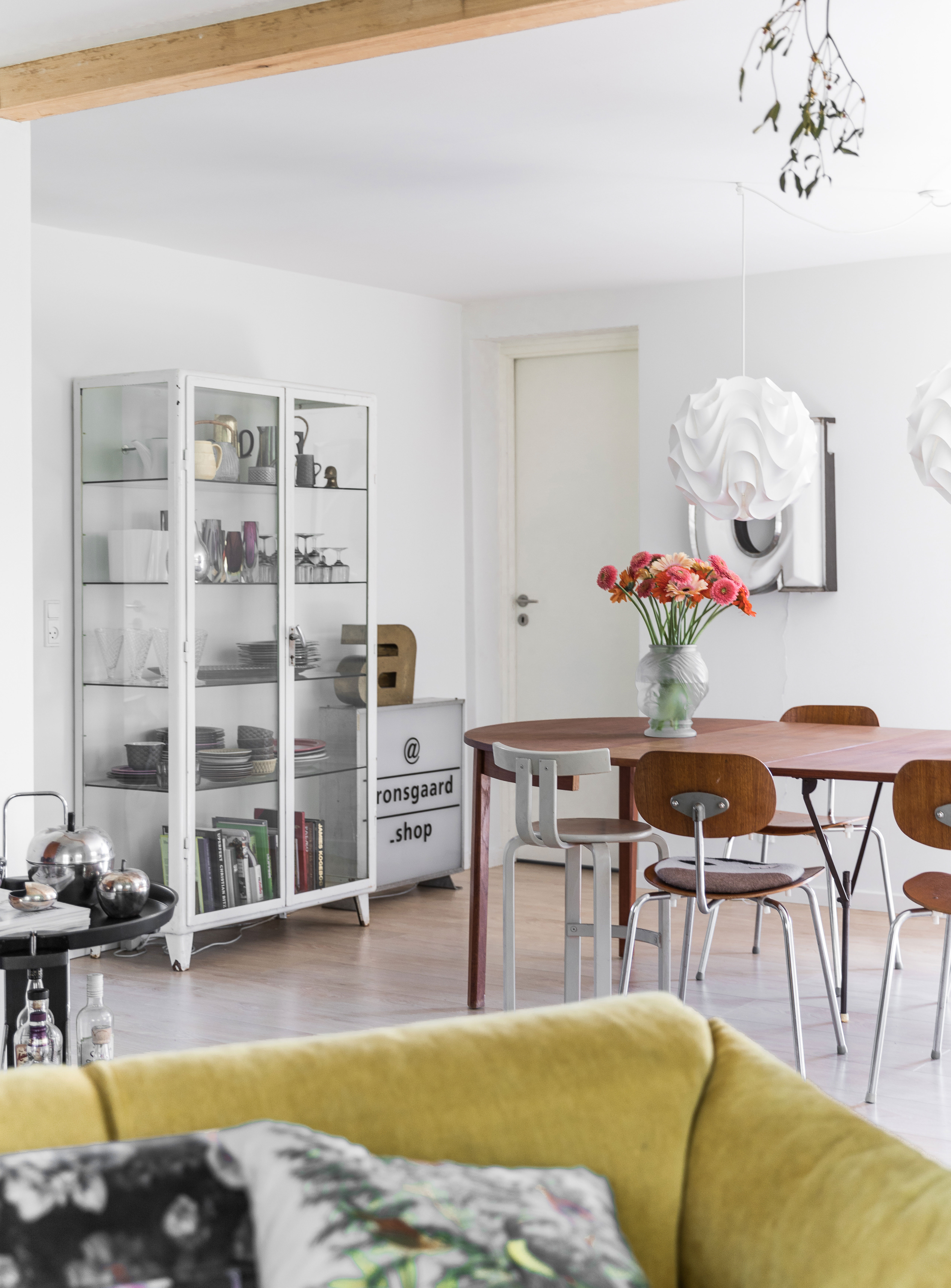 Omkring det gamle teaktræsbord står en blanding af vintagestole, bl.a. designet af Egon Eiermann. Over bordet hænger to vintagelamper fra Le Klint.